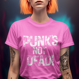 A person with short lavender and neon orange hair wears a bright pink graphic T-shirt with the distressed white text 'PUNK'S NOT DEAD!' against a dark, colorful blurred background.